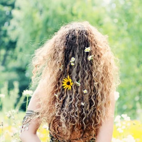 Boho style hairstyle for long naturally curly hair with center part and floral accents