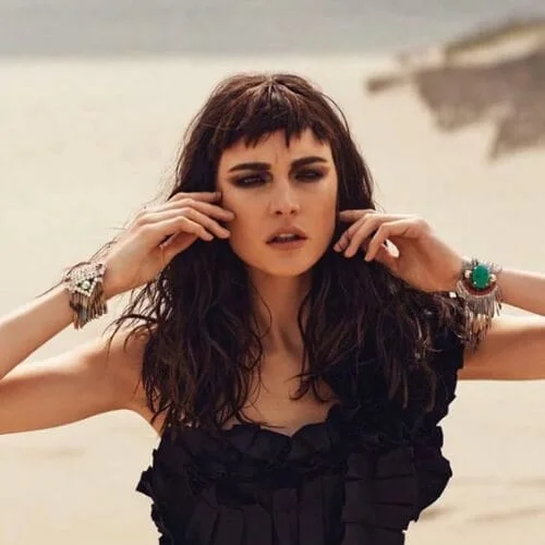 Stylish baby bangs paired with long dark chocolate brown hair creating a bold, fashion-forward look