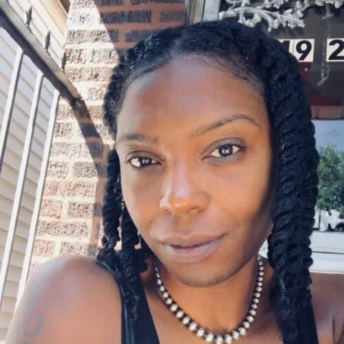 A woman in black tank top with necklace