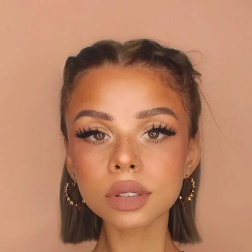 Young woman with braided short straight hair styled in center part with gold earrings