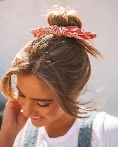 Elegant bun hairstyle for medium-length hair featuring colorful hair accessory and face-framing bangs
