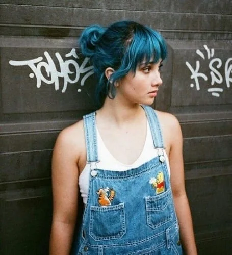 Black hair with blue highlights, blue bangs, and blue tips in messy bun