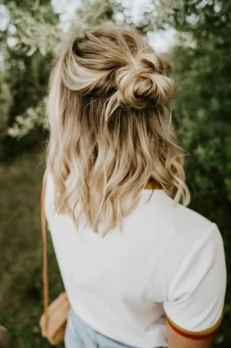Messy half bun Thanksgiving hairstyle for wavy hair - trendy and stylish holiday hair look