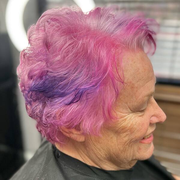 Fabulous Pink Purple Hair on Women over 70 - a woman wearing black salon cape.