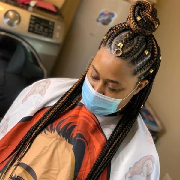Semi Top Bun Kinky Lemon Braided Hair - A woman wearing white salon cape