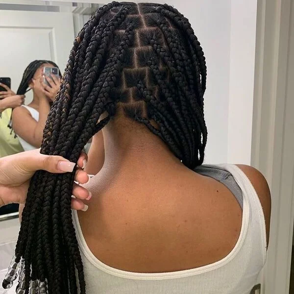 Short knotless box braids with beads - a woman wearing white tank top.