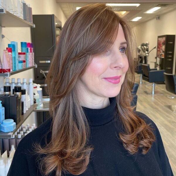 Well-Blended Caramel Highlights with Curtain Bangs - a woman wearing black turtle neck top.