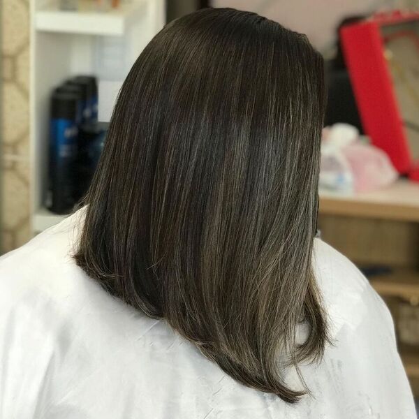 A-line Long Bob Haircut - a woman wearing white salon cape.