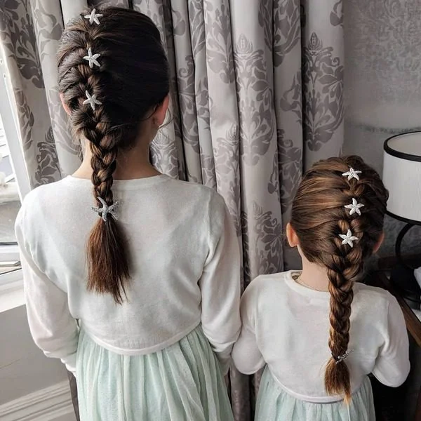 Braid Pigtail with Starfish Accent Flower Girl Hairstyles- girls is wearing white long sleeves top with green skirt.