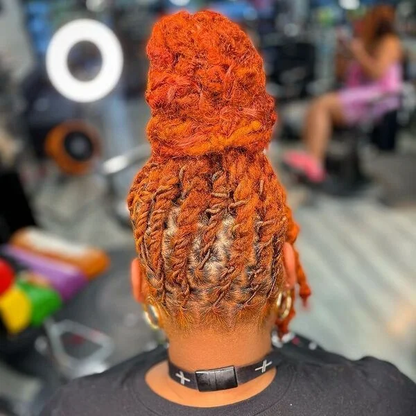 Full Bun Orange Box Dreads - a woman wearing gold loop earrings with black shirt.