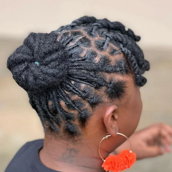 Full Bun with Fringe Dreadlock Hairstyles for Women - a woman wearing black shirt with orange loop earrings.