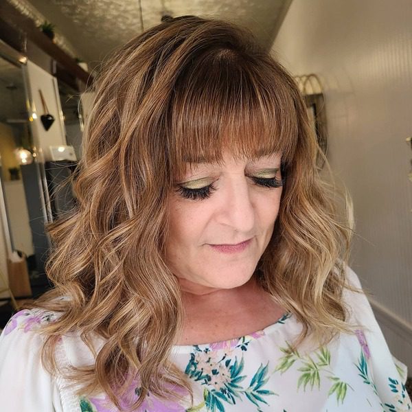 Loose Curls Balayage with Bangs - a woman wearing floral top.