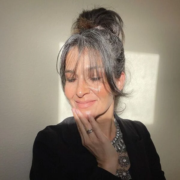 Messy Bun with Wispy Fringe - a woman wearing black coat.