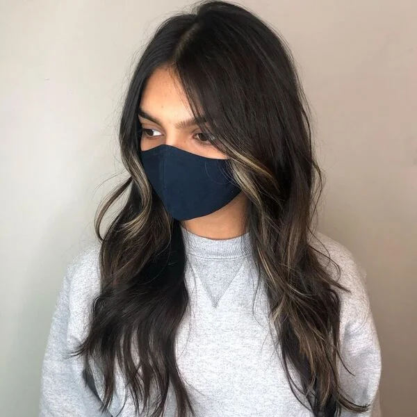a woman wearing black mask and light gray sweater
