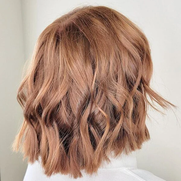 Youthful copper blonde choppy layered bob with wavy texture - rejuvenating short sassy haircut ideal for warm skin tones
