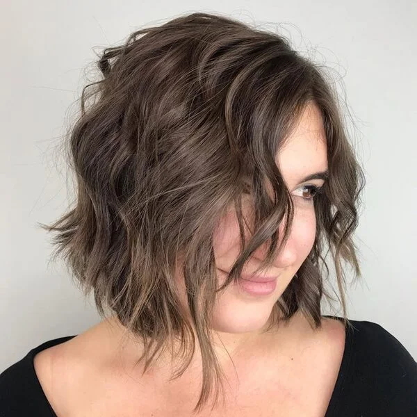 Cute side-swept bob with soft loose waves in natural brown - versatile short sassy haircut that balances sassiness with feminine charm