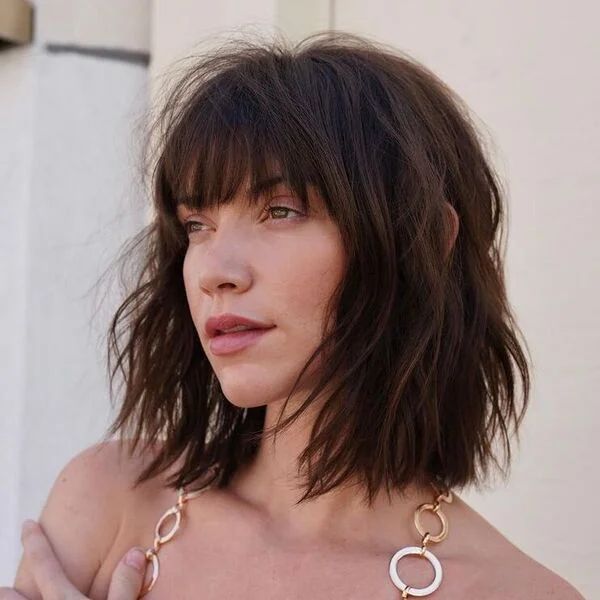 Textured dark brown bob with full forehead bangs and piece-y layers - versatile short sassy haircut ideal for oval and long face shapes