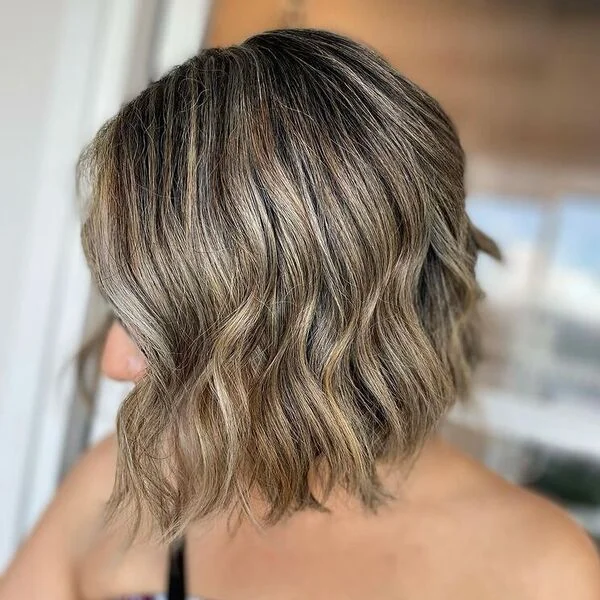 Glamorous wavy silver-brown lob with collarbone-grazing length - feminine short sassy haircut that suits warm skin tones