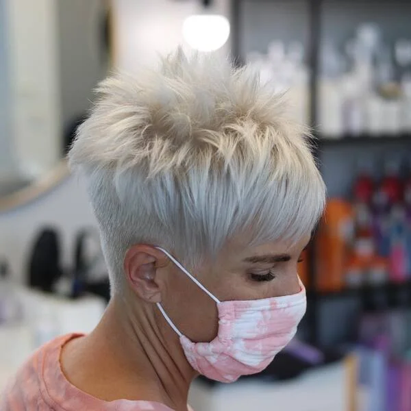 Trendy platinum white spiky pixie cut with voluminous texture and side-swept bangs - cool-toned short sassy haircut for dramatic impact
