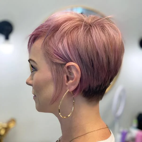 Face-slimming textured pixie cut with blush pink color and heavy sideburns on black base - edgy short sassy haircut for cool skin tones
