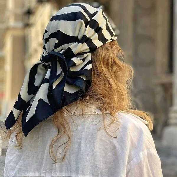 A woman wearing black and white scarf in white polo