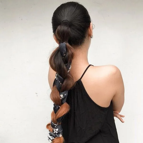 a woman wearing black halter top had her hair styled to a Braided Scarf Ponytail