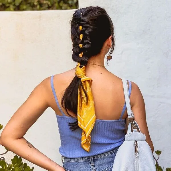 A woman wearing purple tank top with bag