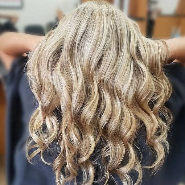 Woman showing subtle lowlights curly blonde graduation hairstyle wearing black cape