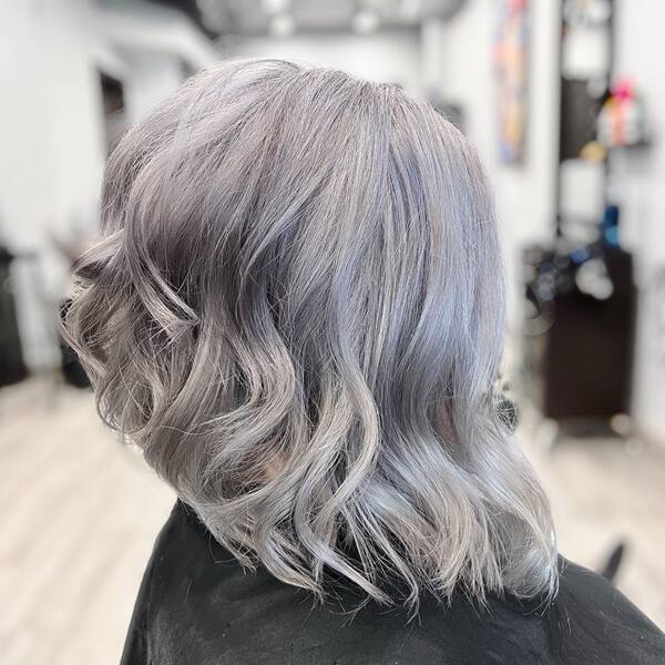 a woman wearing salon cape with platinum silver curled angled bob
