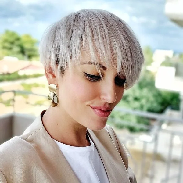 A woman wearing white inner shirt with beige coat with her Drop Down Icy Blonde Hairstyle